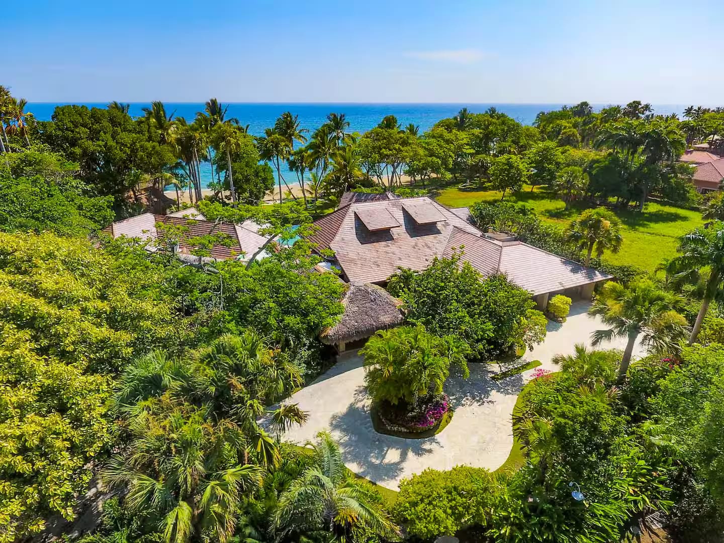 Aerial view of the villa among the trees, with the ocean behind