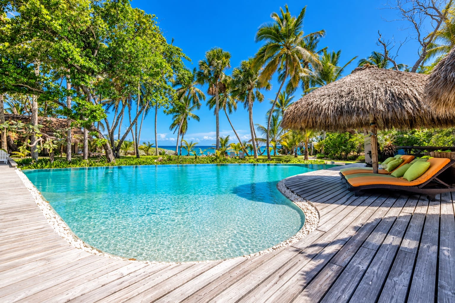 Infinity pool with wooden deck and palapa facing the Caribbean Sea