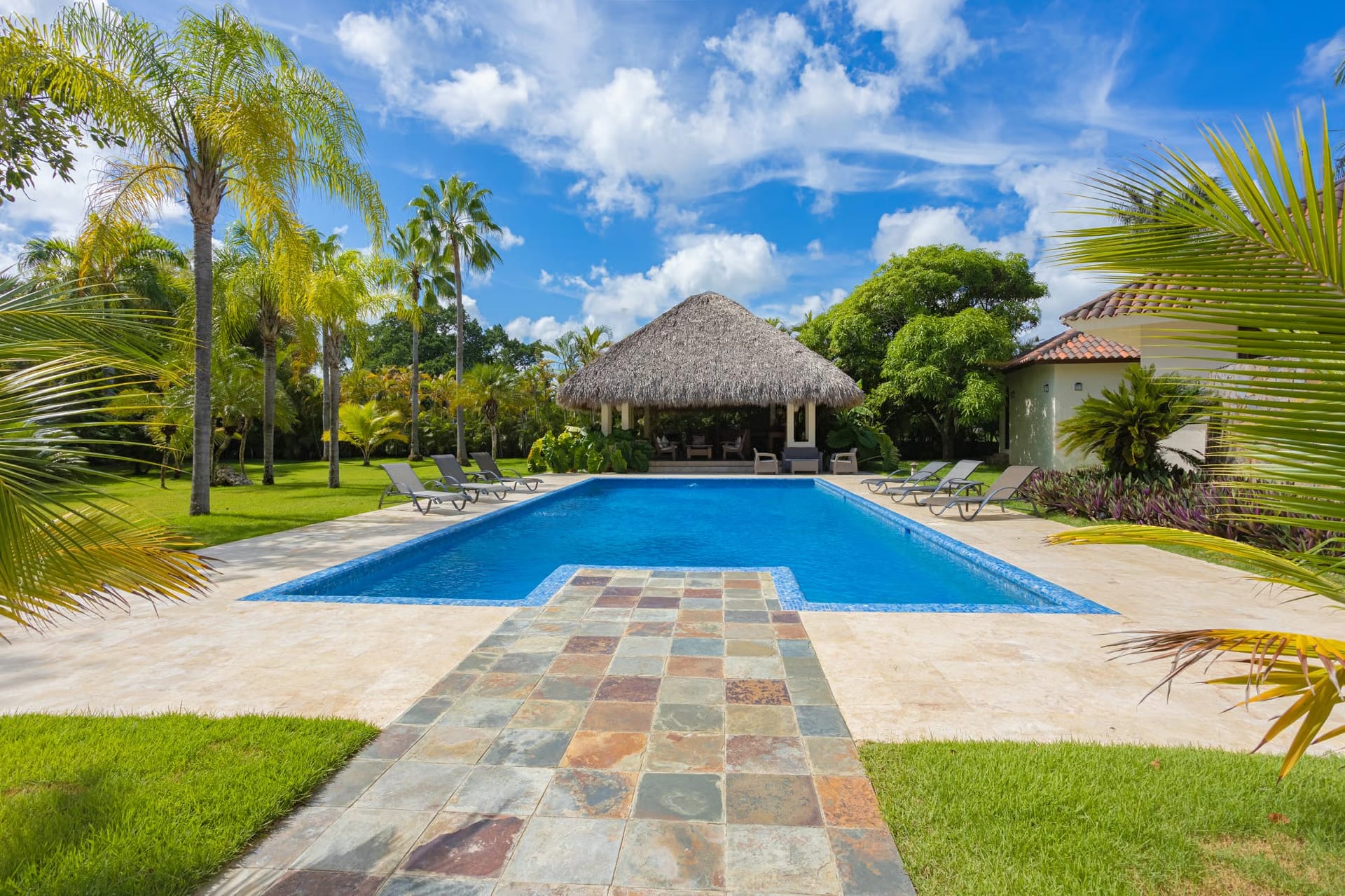 Pool with stone walkway leading to the thatched gazebo